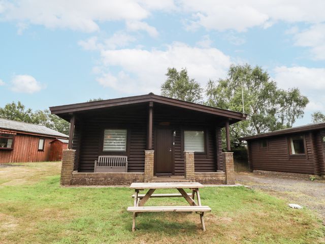 A log cabin with a picnic table in front at Farnes Lodge Longframlington