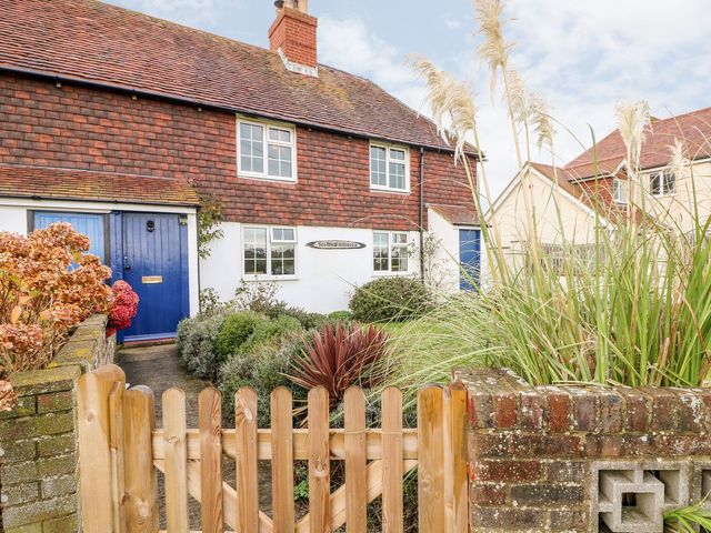 A front view of a house with a blue door and garden plants at 2 Seaview Cottages Normans Bay near Bexhill-On-Sea