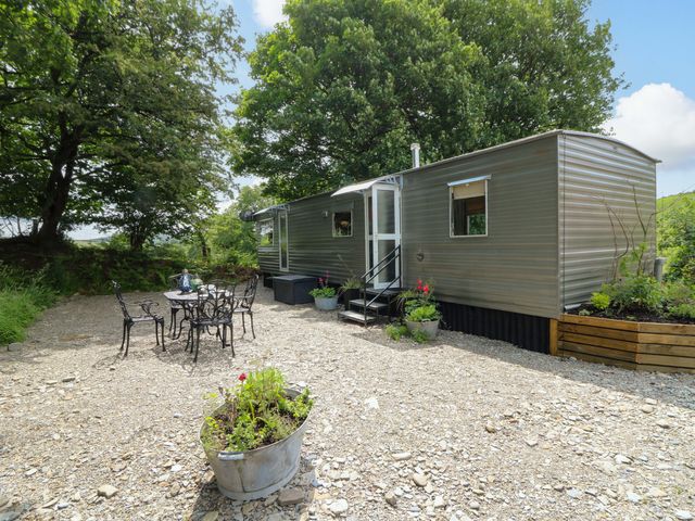 An outdoor seating area with a trailer and table at Gwybedog Llanwrda