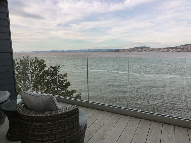 A balcony with chairs and table overlooking water and bridge at Lazy Bulldog in 