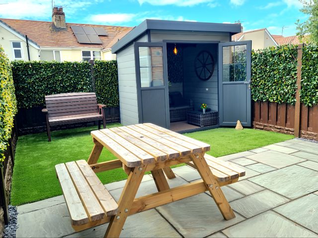 A garden with a table and shelter at Hafan Rhos in Rhos-On-Sea