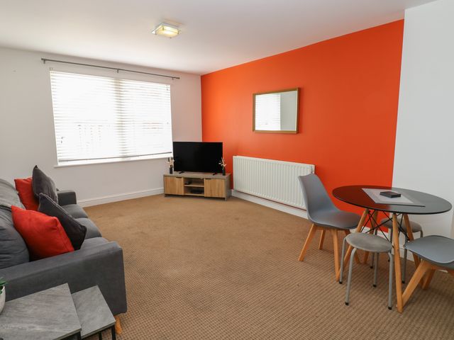 A living room with a sofa and television at Curwen Apartment in Workington