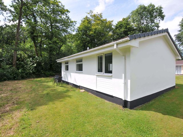 A bungalow with chairs in the garden at 4 Rosecraddoc Lodge Holiday Bungalows Liskeard