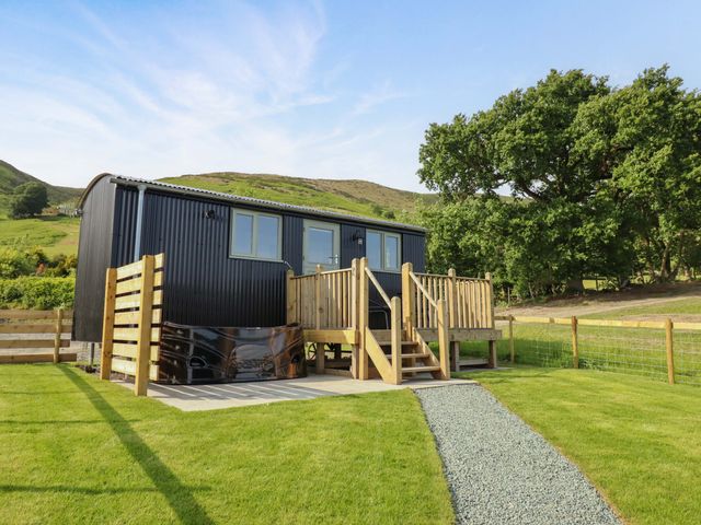 A cabin with a deck and steps in a grassy area at Cheviot in Oswestry