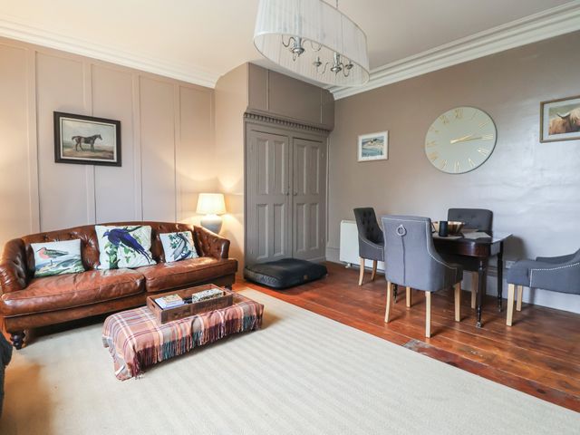 A living room with a leather sofa and dining table at Elstronwick Hall Apartment