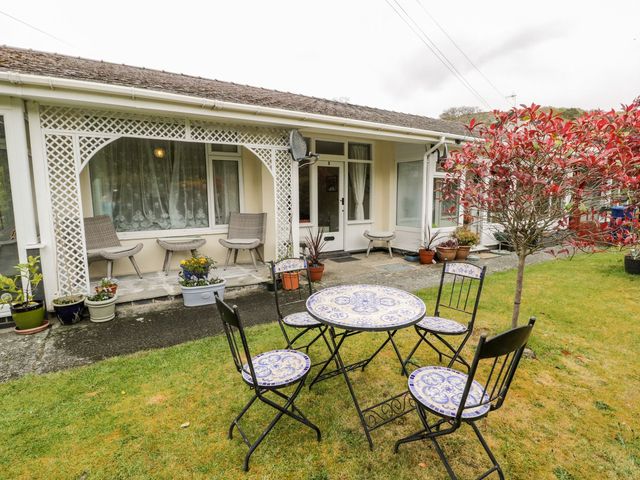 A garden with a table and chairs at 3 Riverside Bungalows in Llanbedr