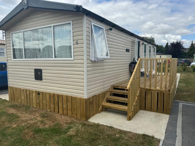 A mobile home with a wooden steps and railing at Pinewood in Kidlington