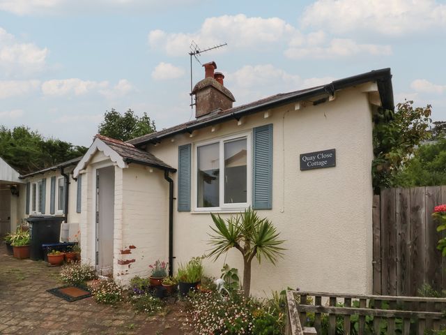A cottage with potted plants and a sign at Quay Close Cottage 