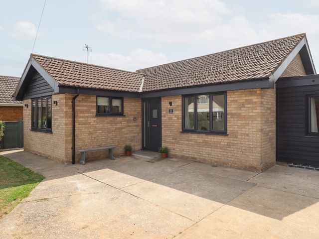 A front view of a bungalow with a pathway and plants at Sandy Toes in Trusthorpe