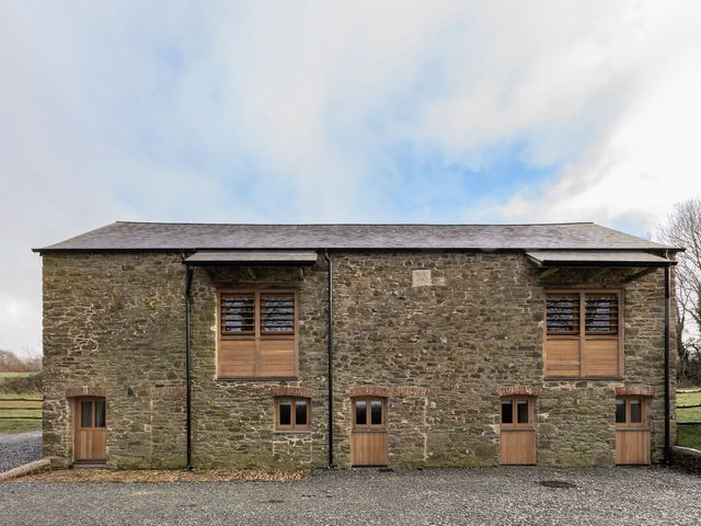A stone building with wooden windows and doors at Lower Walreddon Farm Tavistock
