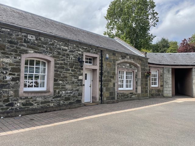 An outdoor view of a stone building with windows and a door at Coach House 5 Perth