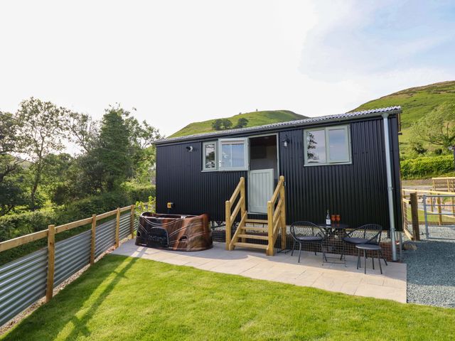 A hot tub and seating area outside a cabin at Charollais in Oswestry