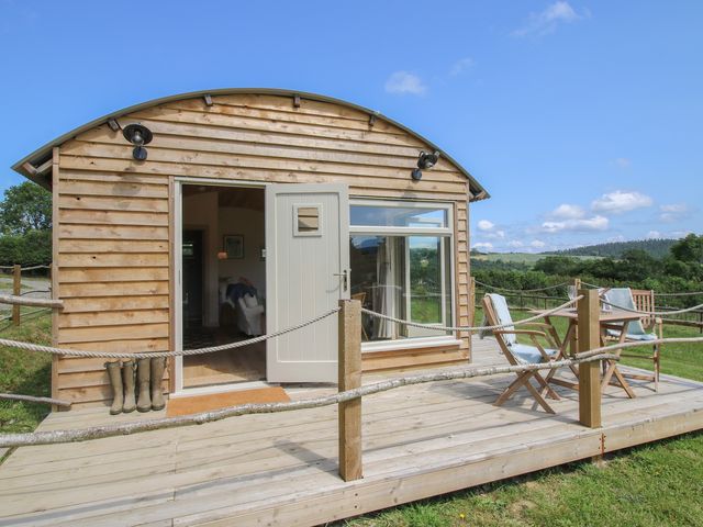 A wooden cabin with a deck and chairs at Owl's Hollow in Chapel Lawn near Clun