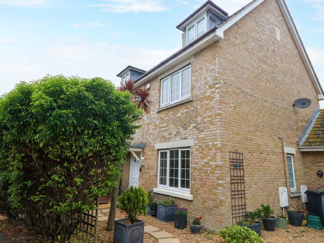 An outdoor view of a house with plants and a pathway at Fairways House in Weymouth