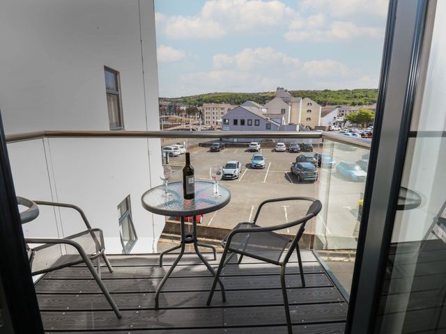 A balcony with a table and chairs overlooking a parking lot at Harbourside Apartments in Whitehaven
