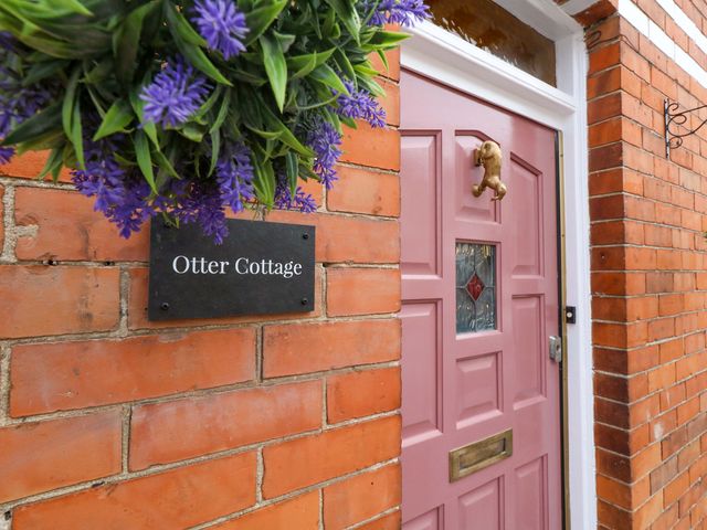 A pink door with a nameplate at Otter Cottage in Weymouth