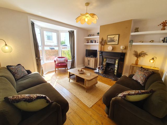 A living room with sofas and a fireplace at Otter Cottage in Weymouth