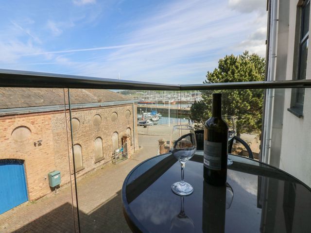 A balcony with a wine bottle and glass overlooking a marina at Quayside Apartments Whitehaven