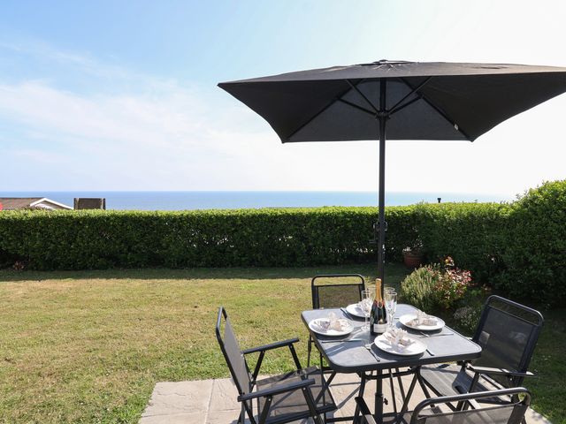 A garden with a table, chairs, and umbrella overlooking the sea at Stella Maris in Torpoint