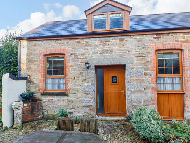 An exterior view of a stone building with wooden door and windows at The Stables in Falmouth