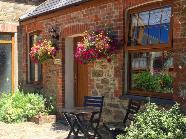 An outdoor area with flowers and seating at Farrier Cottage Budock Water near Falmouth