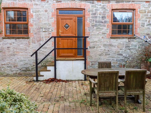 An outdoor area with a wooden table and chairs at Horseshoe Cottage in Falmouth