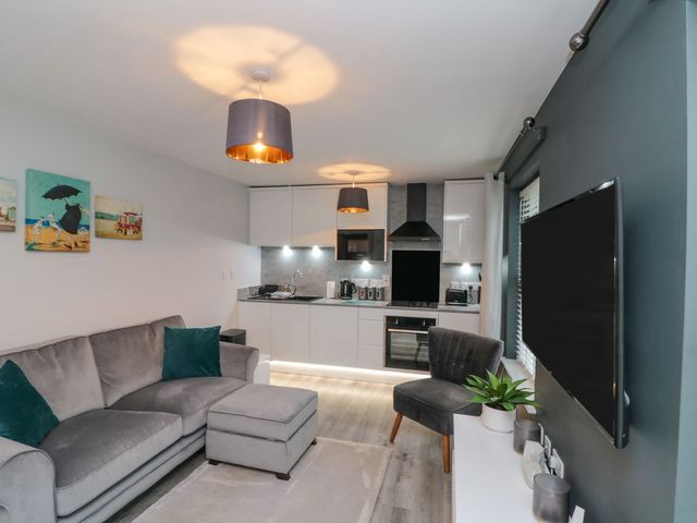 A living room with a sofa and kitchen in Rosie's Retreat Filey