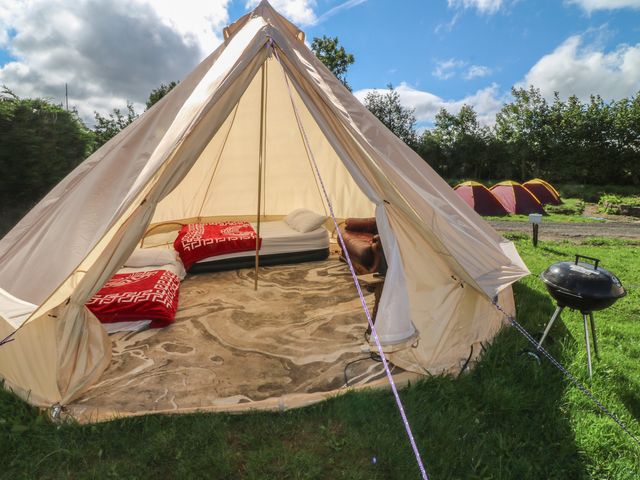 A tent with beds and a grill outside at Bell Tent One