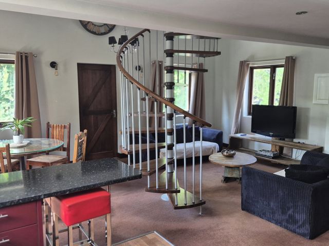A living room with a spiral staircase and seating area at Flat 3, The Old Bakehouse in Telford