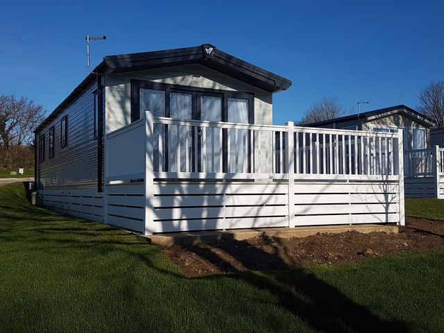 A mobile home with a deck and fence at The Maples, no. 56 St. Austell