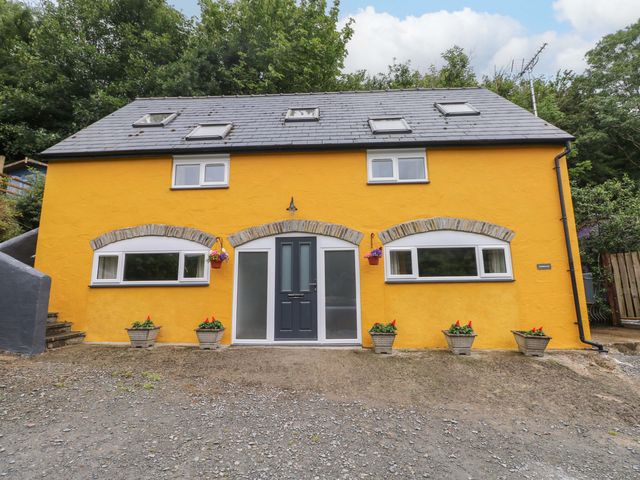 A house with a yellow exterior and gravel driveway at Pendre Barn Llanfyrnach