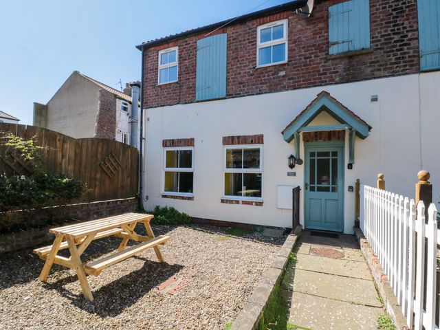 An outdoor area with a bench and a house entrance at Farriers Cottage in Bridlington