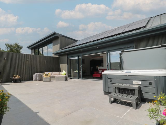 An outdoor area with a hot tub and seating at Noflash Malpal in Bishop Sutton