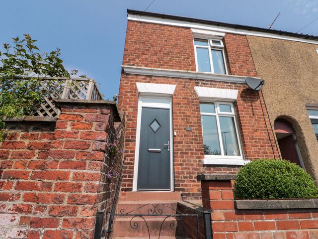 An exterior view of a house with a front door and brick wall at Moot Cottage in Driffield