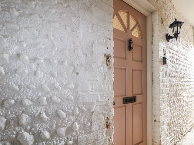 An entrance with a pink door and textured white walls at Lower Floor Flat