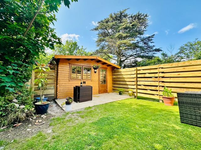 A garden with a wooden shed and patio furniture at Harvey's Lodge in Helston