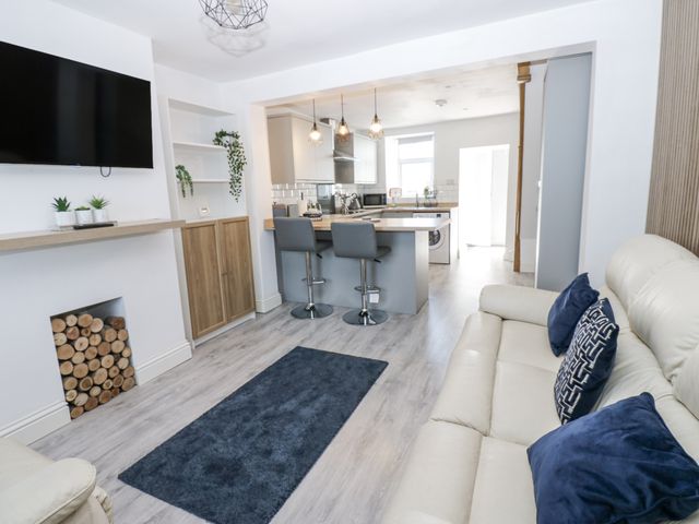 A living room with a television, sofa and kitchen island at Keekle Terrace in Cleator Moor