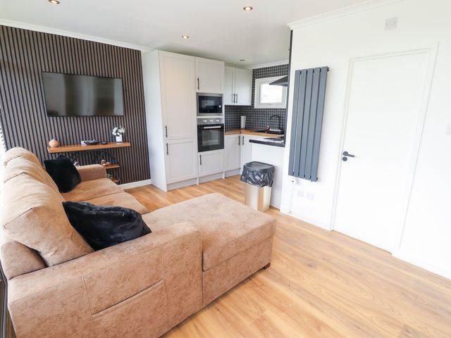 A living room with a sofa and kitchen area at 66 Cherry Park in Skegness