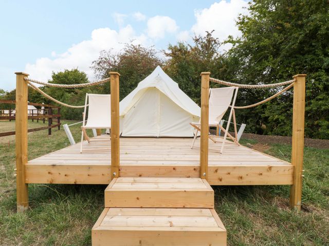 A tent on a wooden deck with two chairs and steps at Bell 3 near Shades Farm near Malmesbury