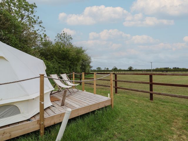 A glamping tent on a wooden deck with chairs at Bell 3 in Shades Farm near Minety