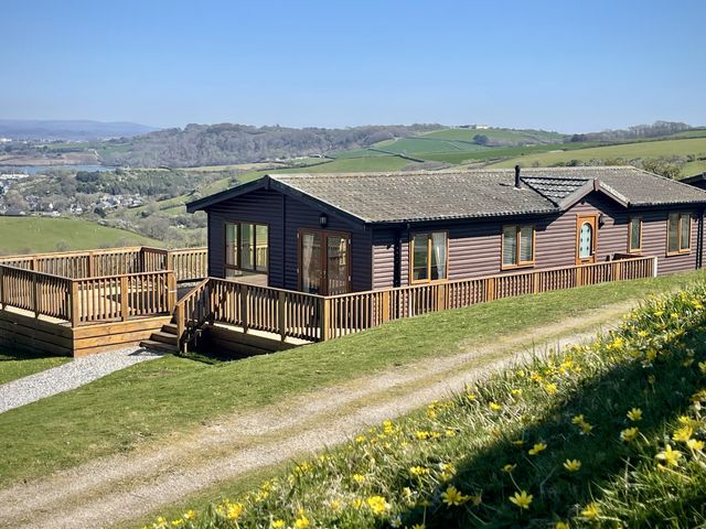 A lodge with a deck and steps at Lowena Lodge Whitsand Bay Holiday Park near Millbrook