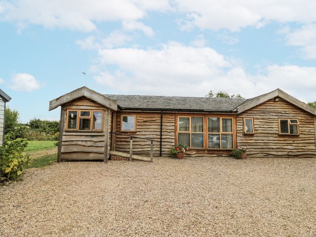 A cabin with wooden exterior and flower pots at Owl Barn in Banbury