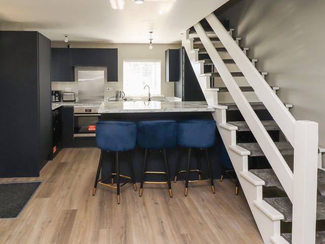 A kitchen with a countertop and bar stools at 3 Longstone Park, Beadnell