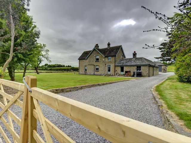 A house with a gravel driveway and garden at The Farm House in Aldbrough St. John near Barton