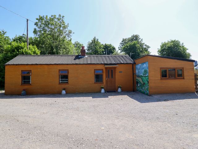 A wooden house with a mural and a gravel area at Haven in Lloc near Holywell