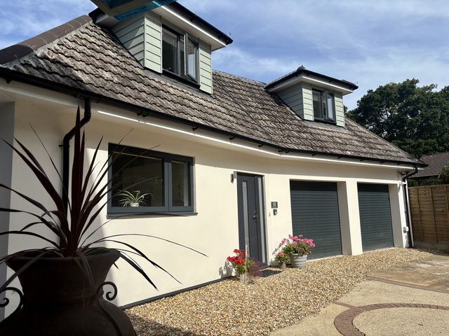 A house exterior with garage doors and flower pots at 8 Church Road Ferndown