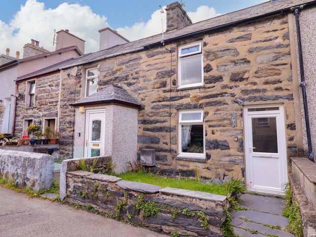 A stone house with a garden and pathway at Bwthynbach in Porthmadog