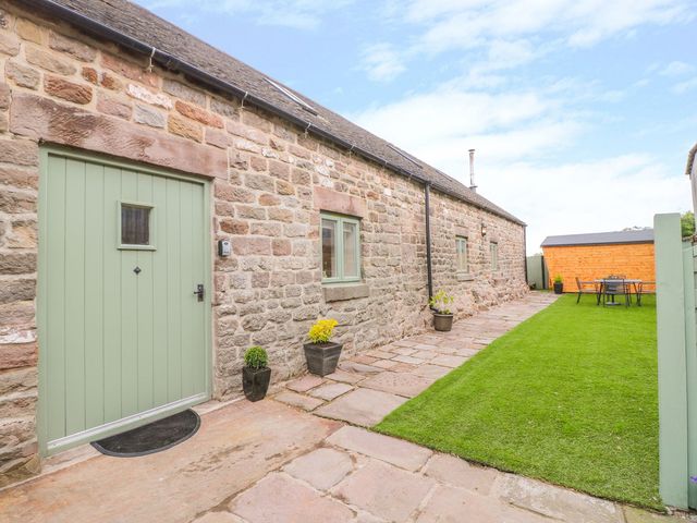 An outdoor area with a stone wall and a garden table at The Barn in Wirksworth