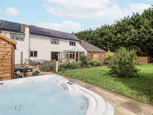 A garden with a hot tub and seating area at Holly Farm near Brantham