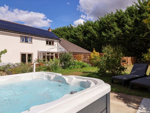 A hot tub with a garden and house in the background at Holly Farm near Brantham
